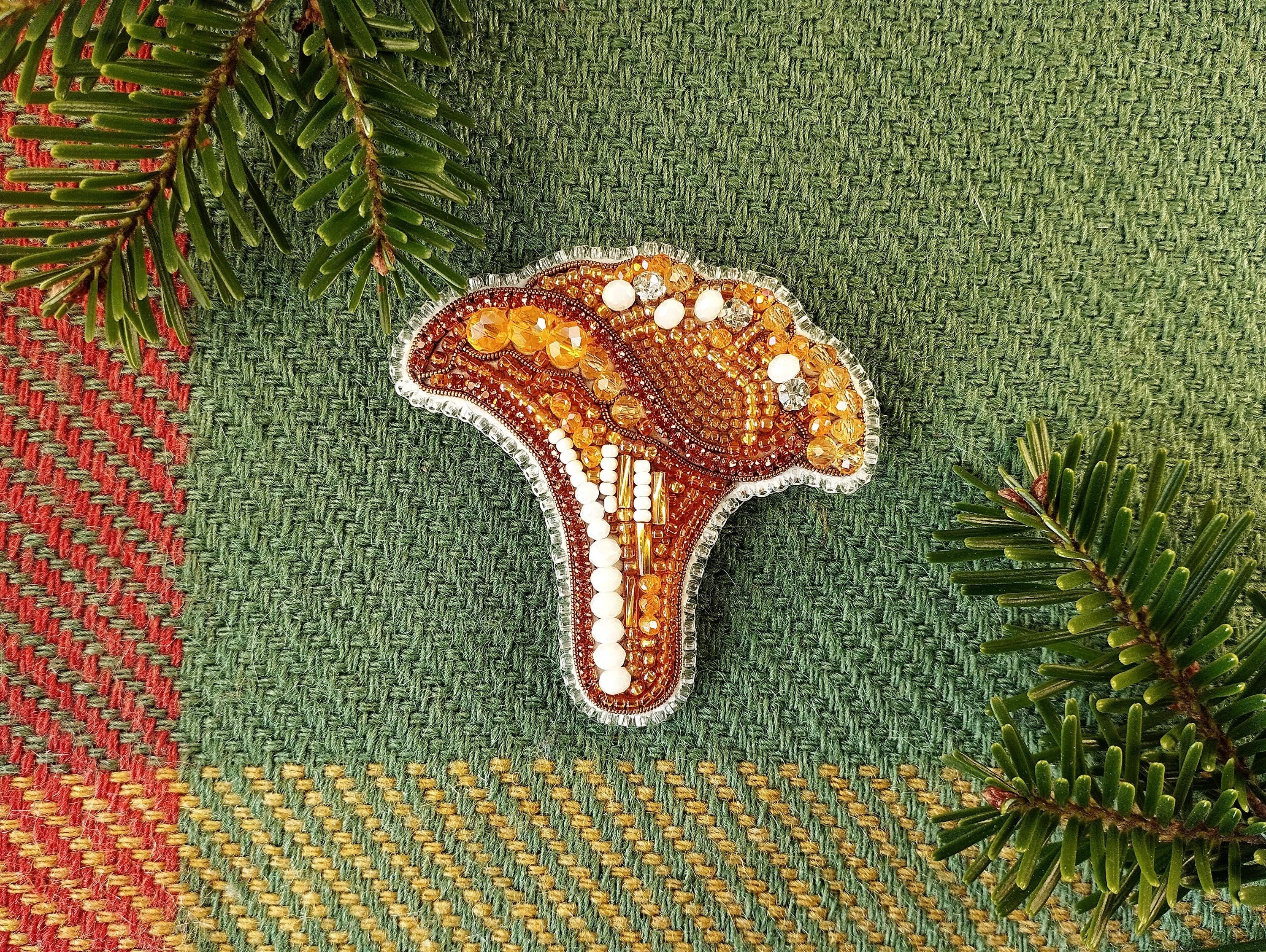 a beaded brooch sitting on top of a green surface